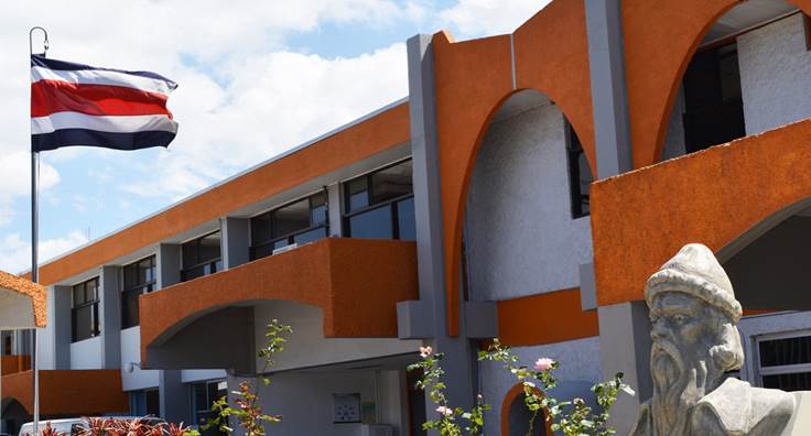 Imagen del edificio de la Imprenta Nacional donde se observa una bandera de Costa Rica y una escultura de Johannes Gutenberg.